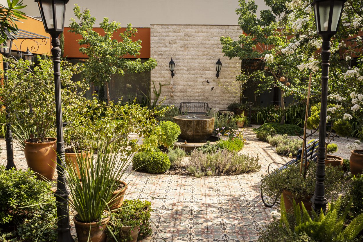 Jardim interno da Ferreira Segantini, com fonte, vegetação e luz natural